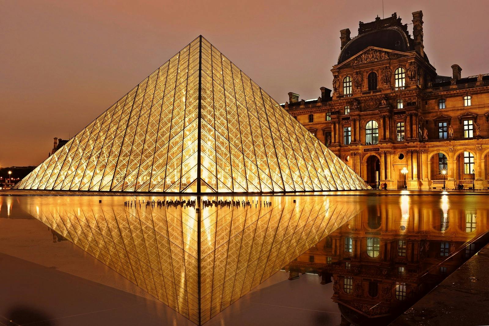 musée du Louvres éclairé la nuit à Paris, on y voit la fameuse pyramide